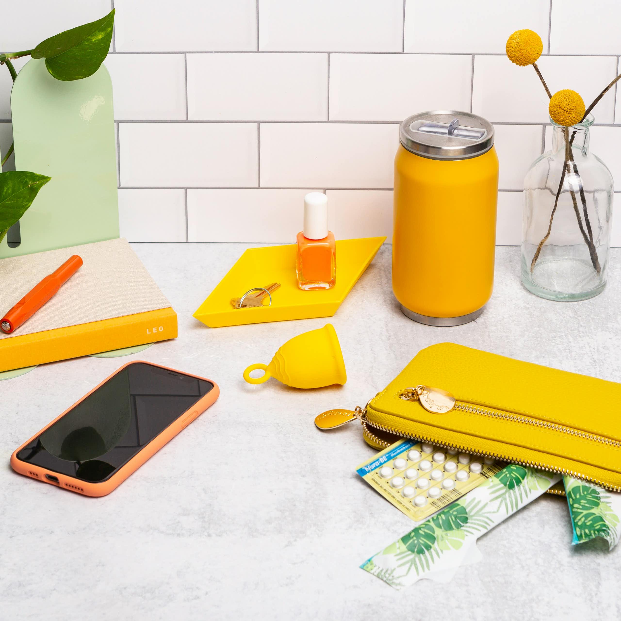Un téléphone, un diva cup et des pilules contraceptives sont étalées sur une table