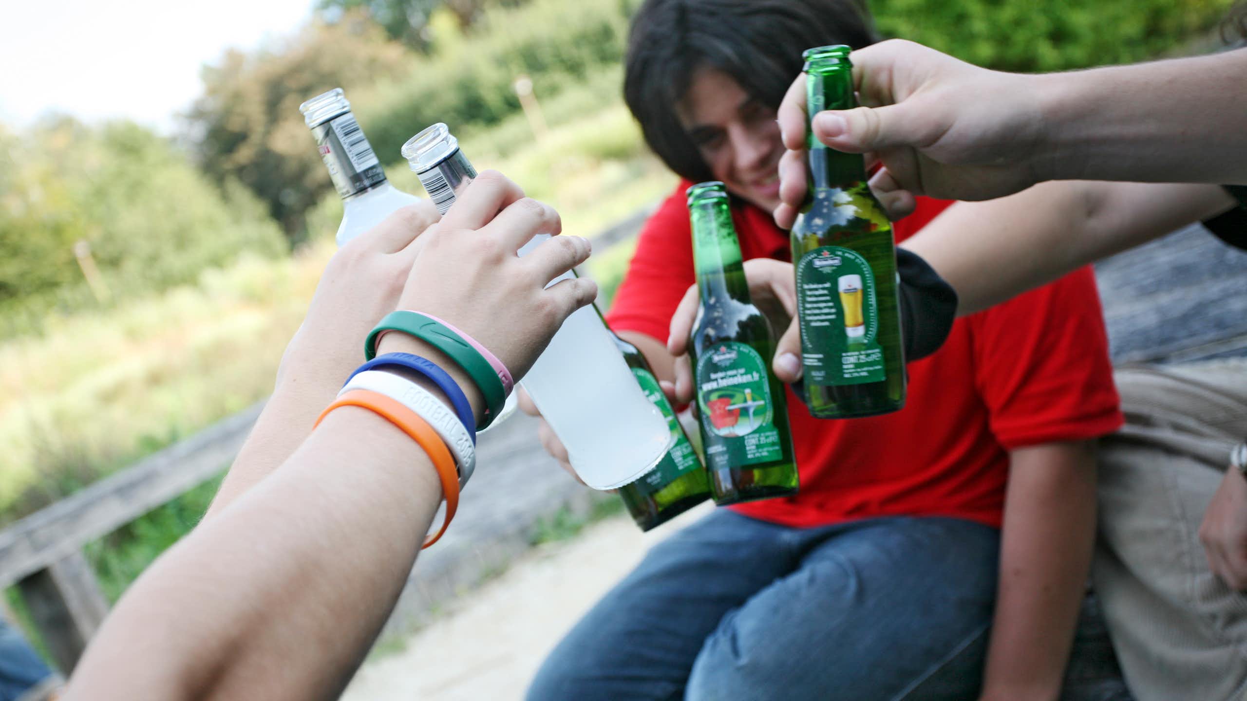 Several people hold glass bottles up for a cheers.