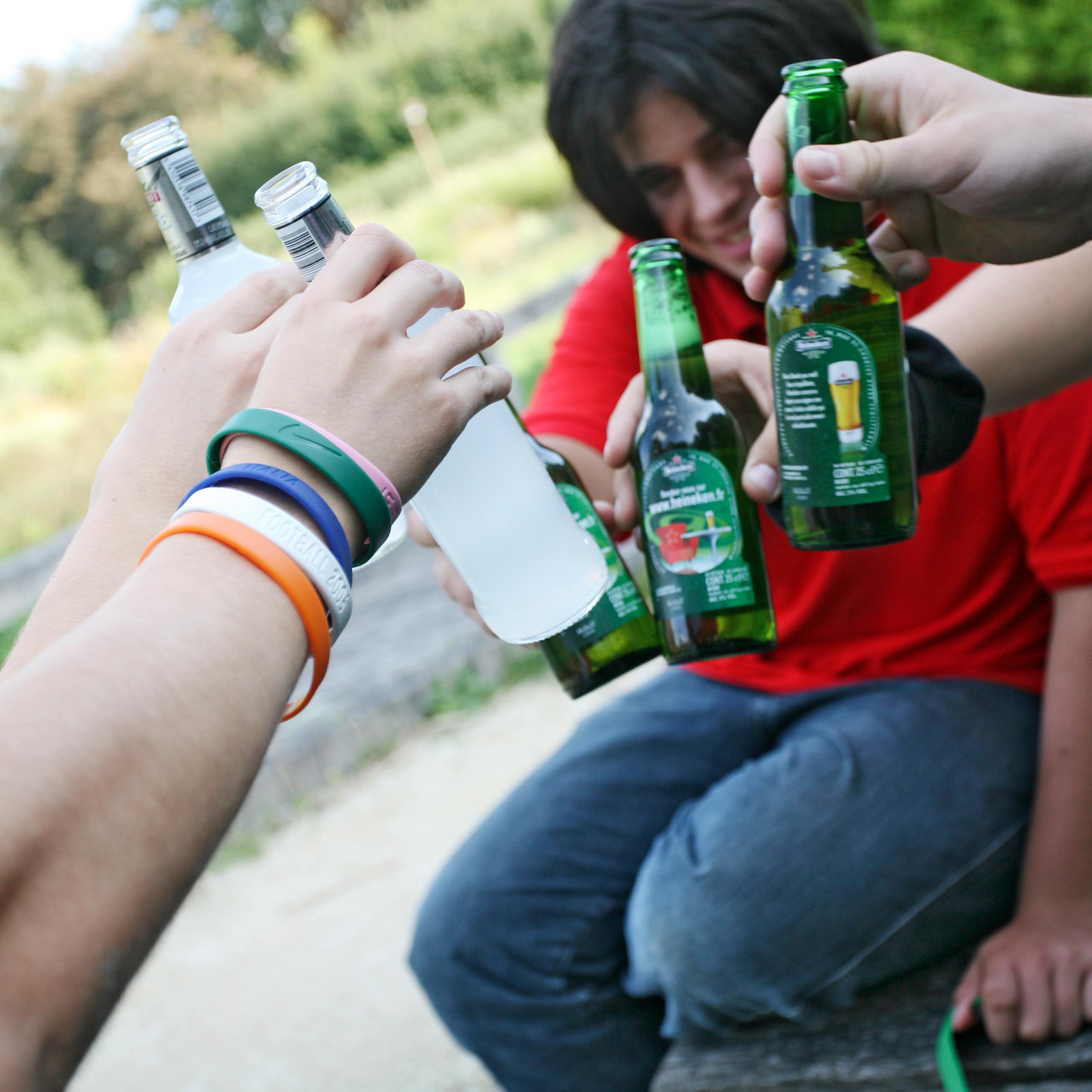 Several people hold glass bottles up for a cheers.