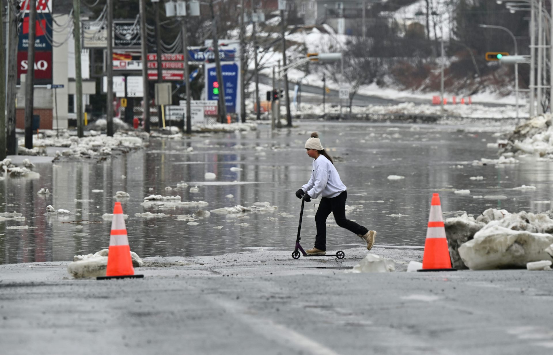 Una joven conduce una scooter por una carretera inundada.