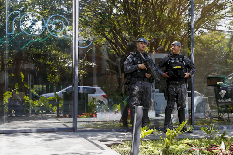 Men in fatigues with guns standf outside a glass building