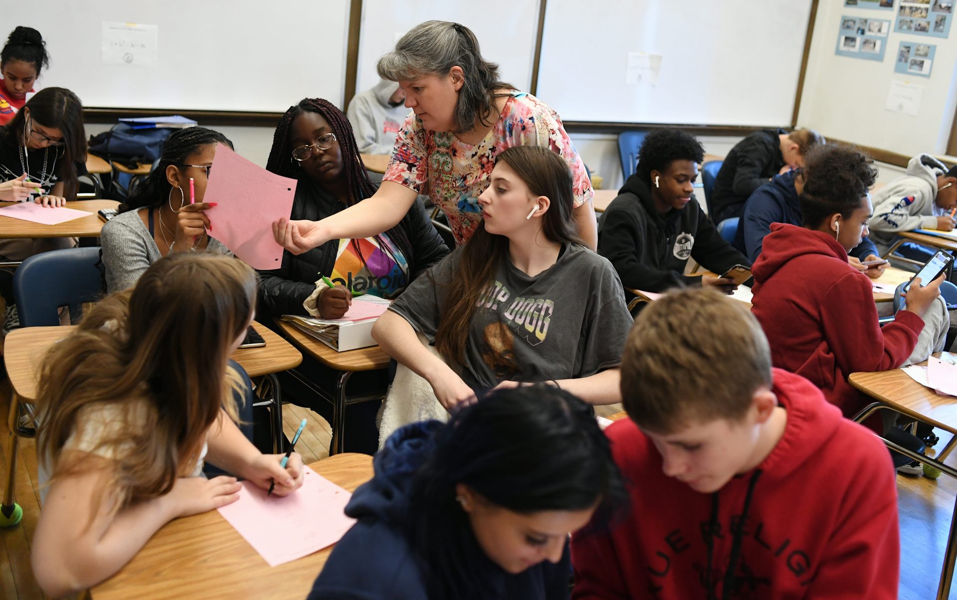 Um adulto está no meio de uma sala de aula movimentada.