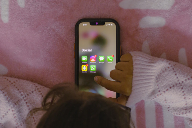 A child laying in bed on their phone.