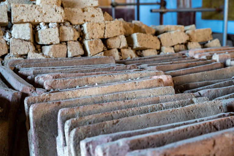 A detail of the neatly aligned ceramic roof tiles and tuff blocks in a newly excavated site in Pompeii, documenting the storage of building materials during renovation.