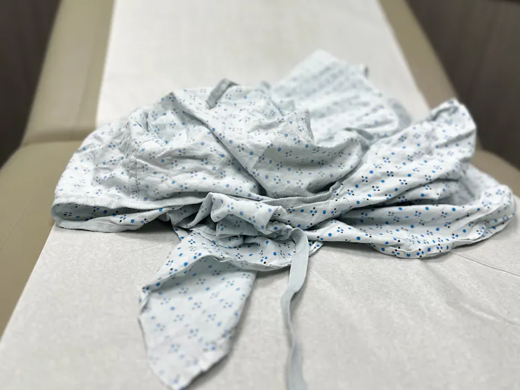 A rumpled medical gown with a light-blue print sits on top of an examining table.