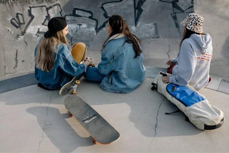Three young people talk at a skate ramp.