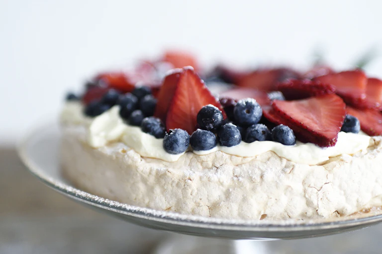 Pavlova with blueberries and strawberries on plate or cake stand