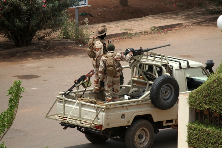 Two soldiers look out from the back of a pick-up truck mounted with a machine gun