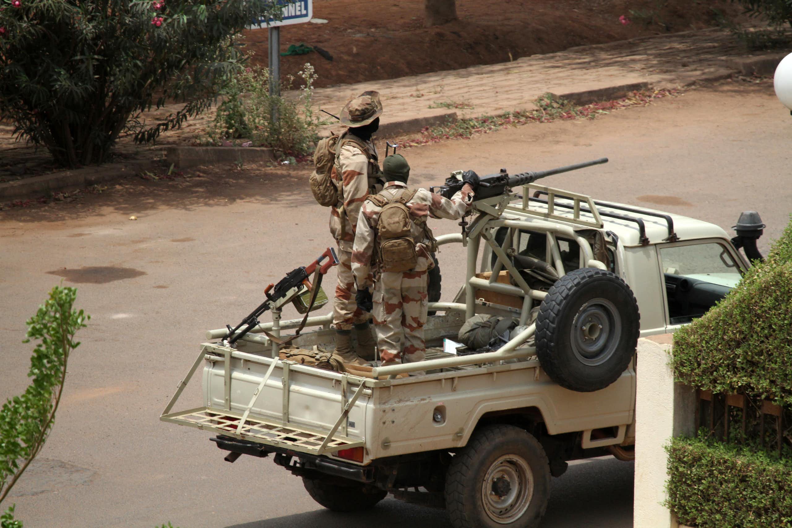 Two soldiers look out from the back of a pick-up truck mounted with a machine gun