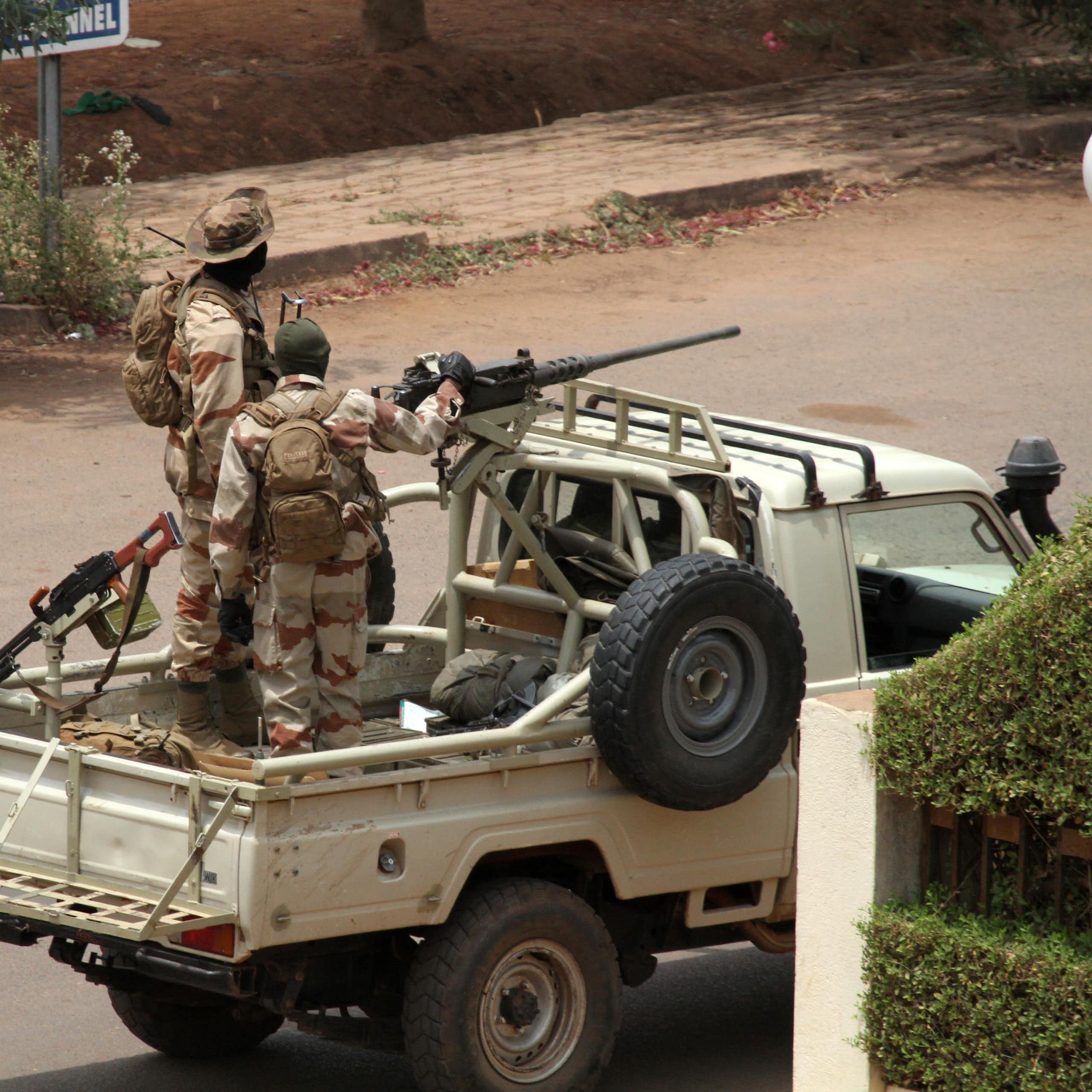 Two soldiers look out from the back of a pick-up truck mounted with a machine gun