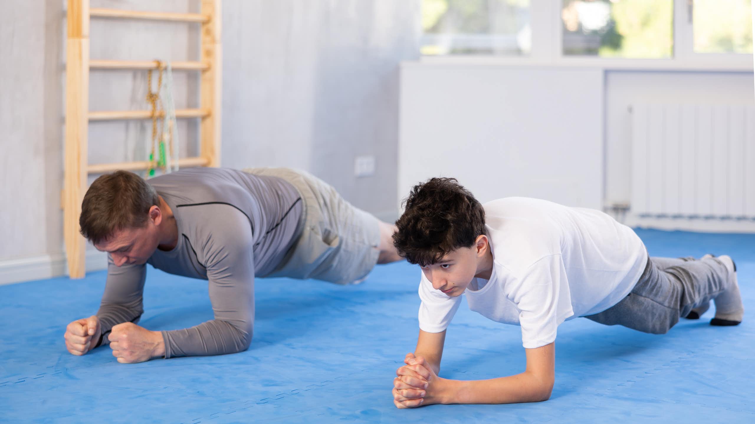 Un adulto y un adolescente apoyados en los antebrazos.