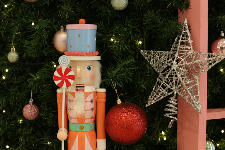 a traditional nutcracker doll in front of a decorated christmas tree