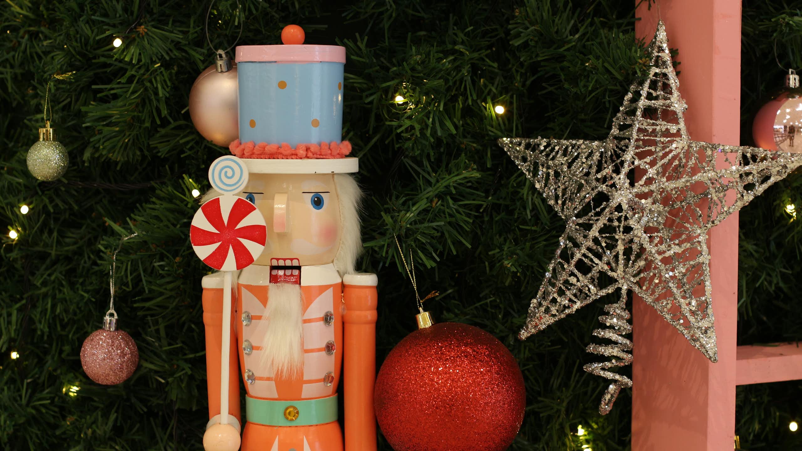a traditional nutcracker doll in front of a decorated christmas tree