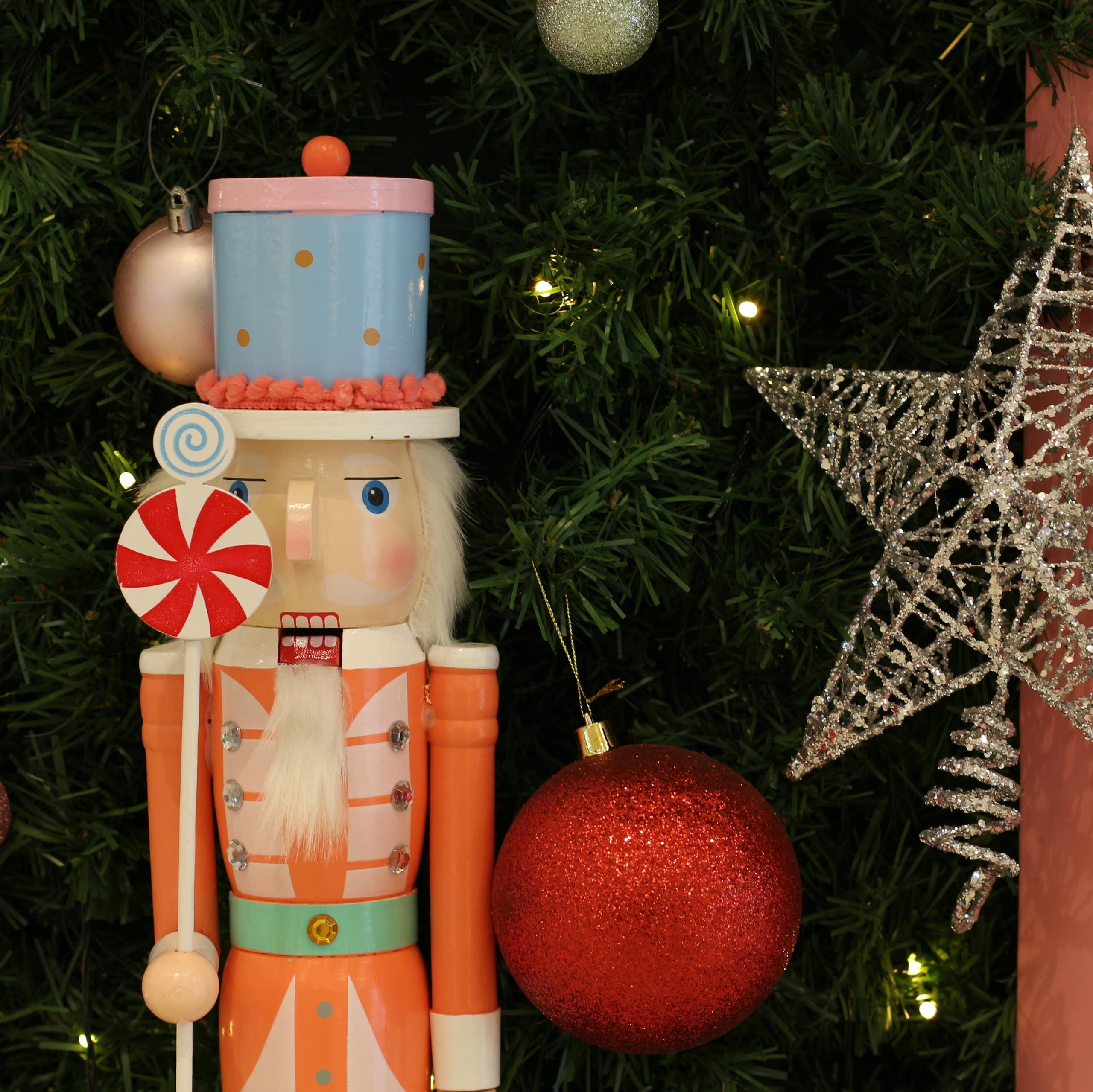 a traditional nutcracker doll in front of a decorated christmas tree