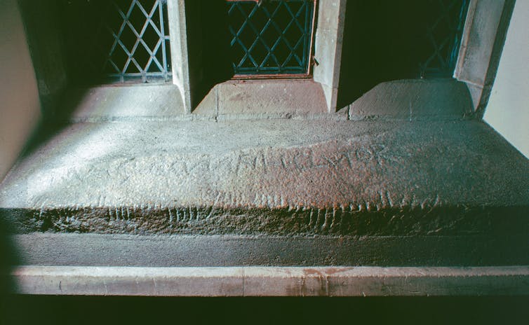 An old stone slab set into a window featuring Ogham writing.