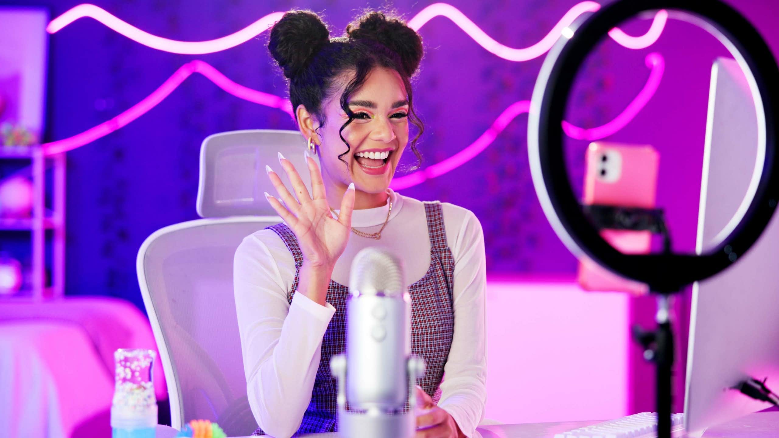 Girl with phone live streaming in neon bedroom for social media audience, fans or followers.