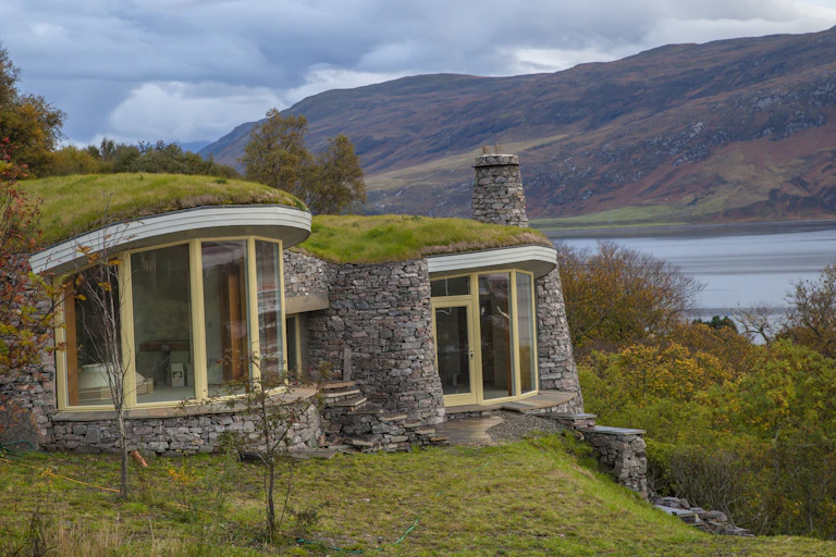 turf covered stone walled homes with loch in background