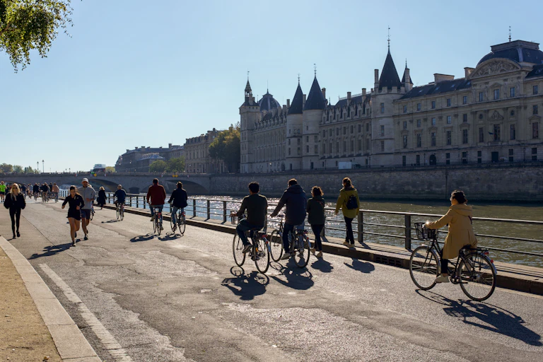Photo de piétons et cyclistes prise à Paris, sur les voies sur berge, en face de la Conciergerie