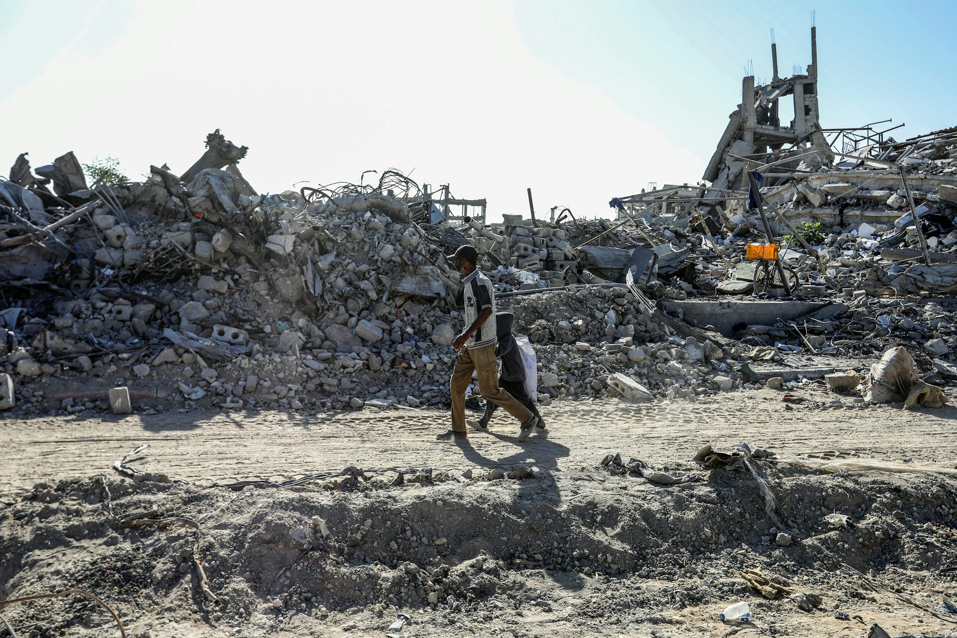 Un padre y su hijo caminan entre ruinas.