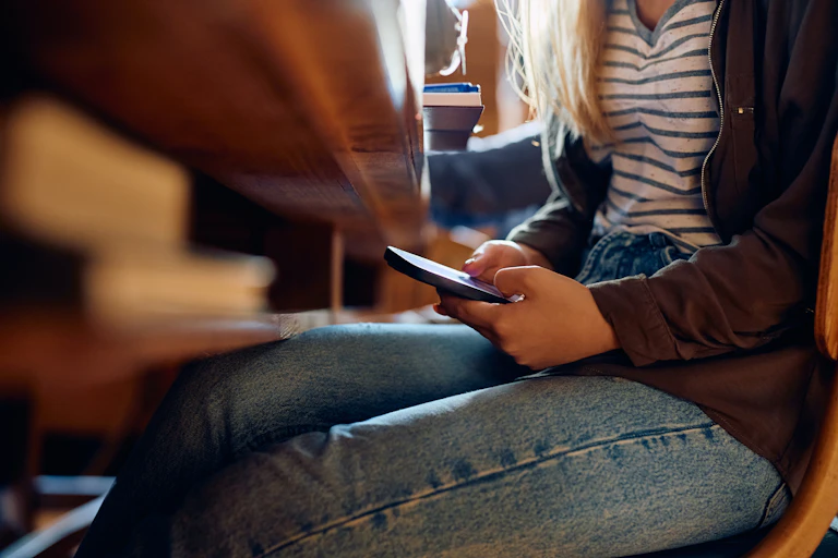Girl looking at phone under desk