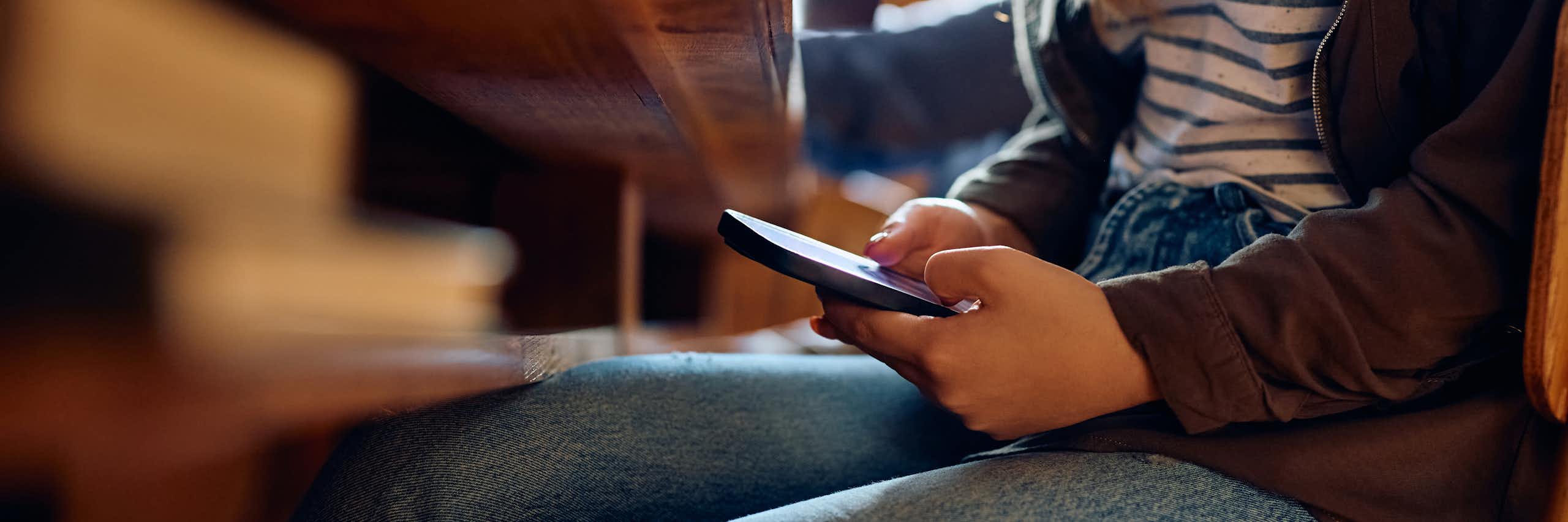 Girl looking at phone under desk