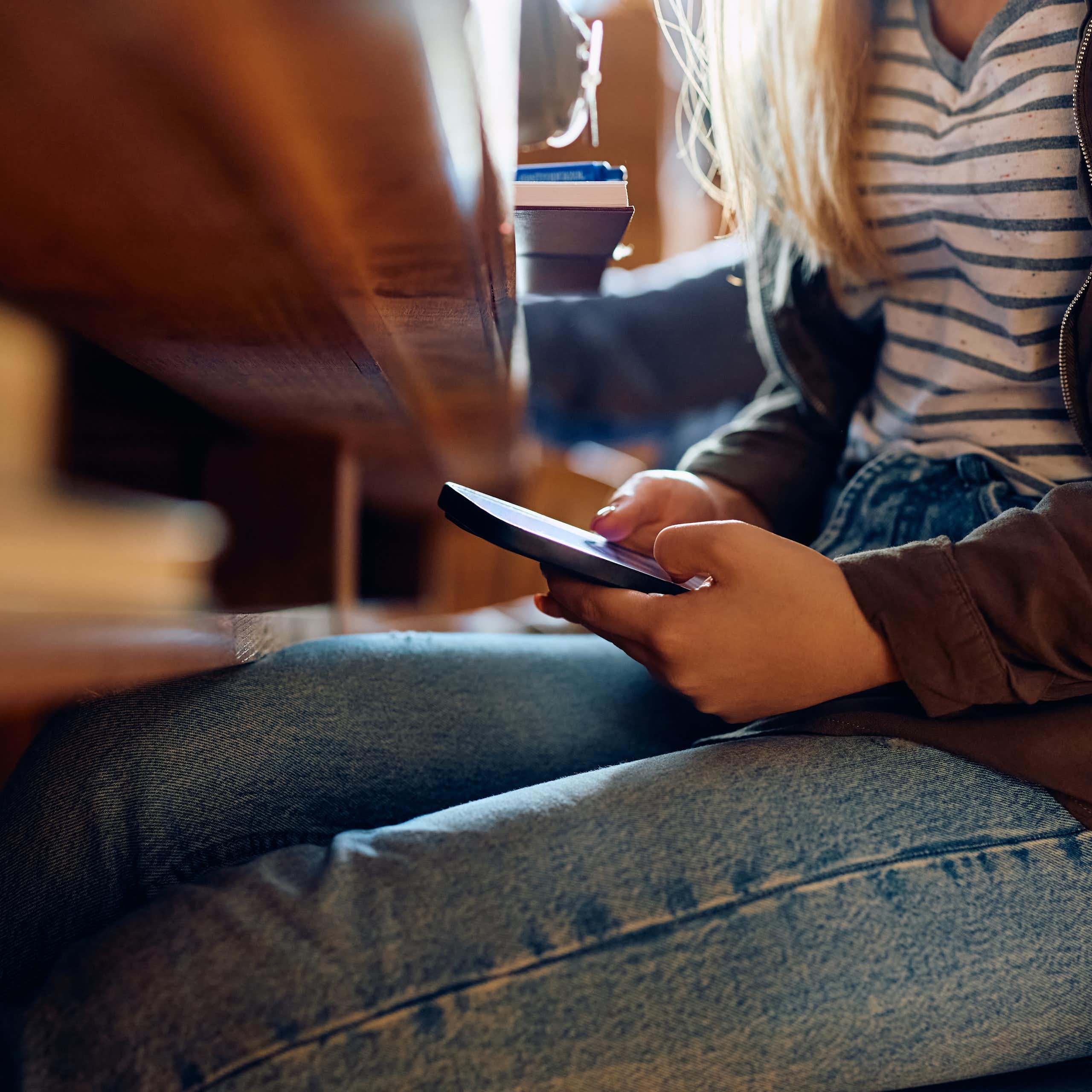 Girl looking at phone under desk
