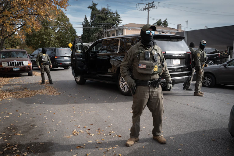 Masked men dressed in military gear surround a car.