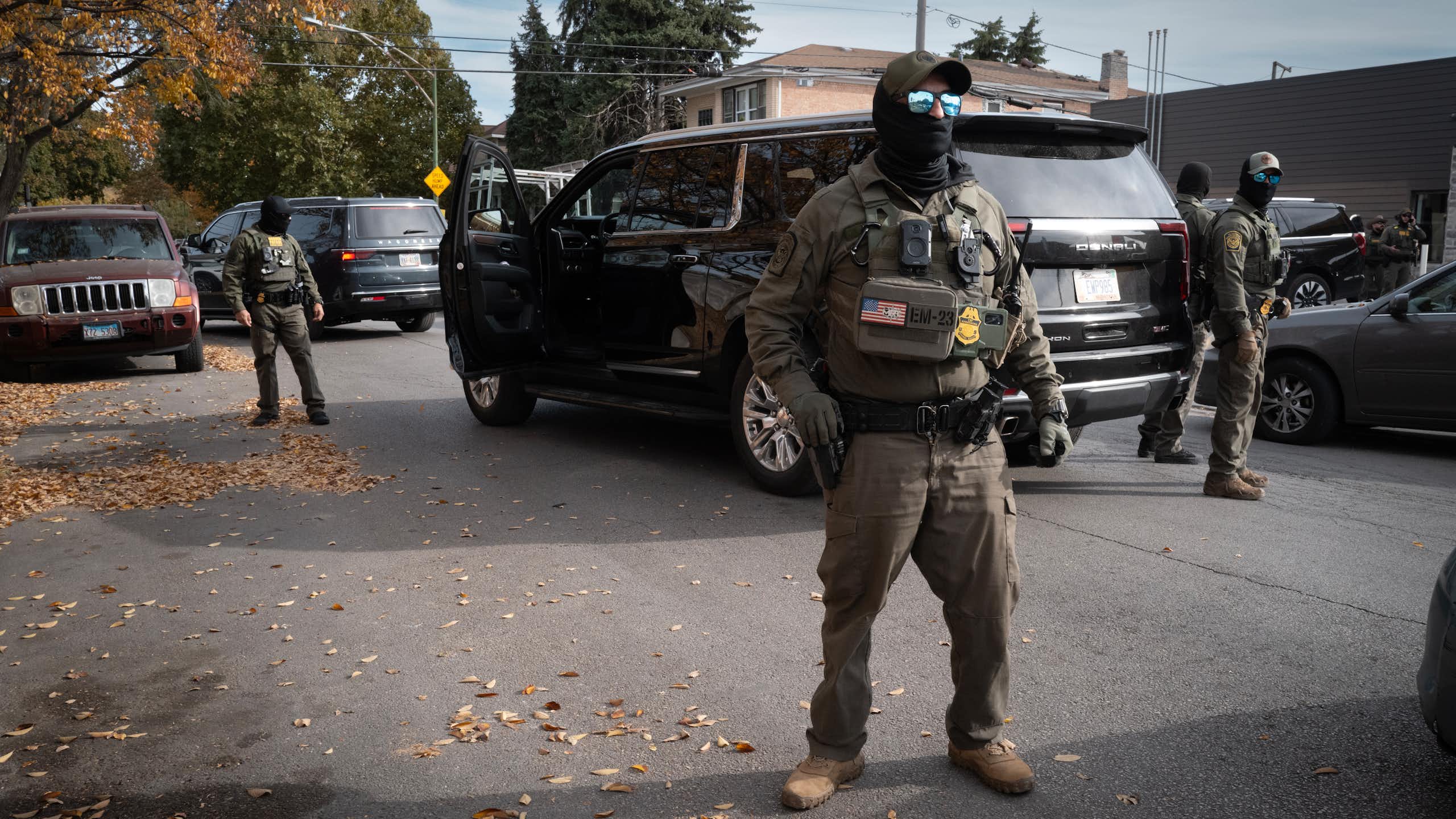 Masked men dressed in military gear surround a car.