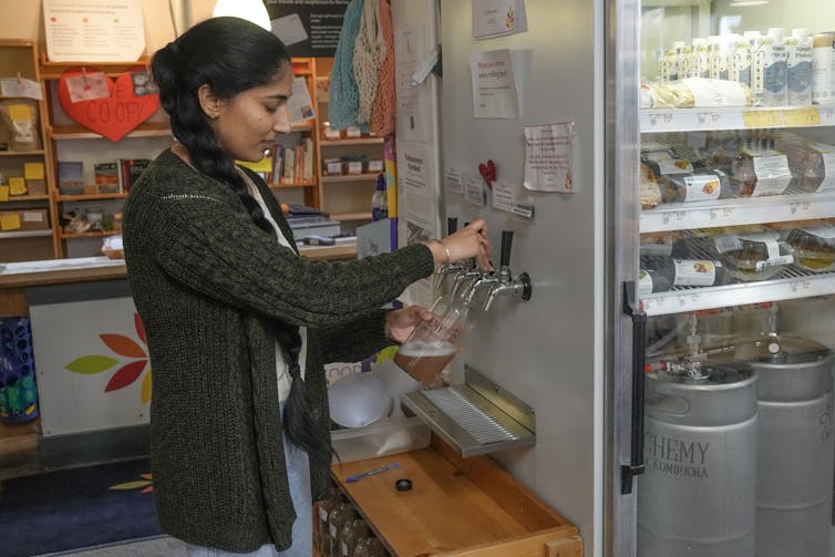 Una mujer sirve una bebida en una tienda.