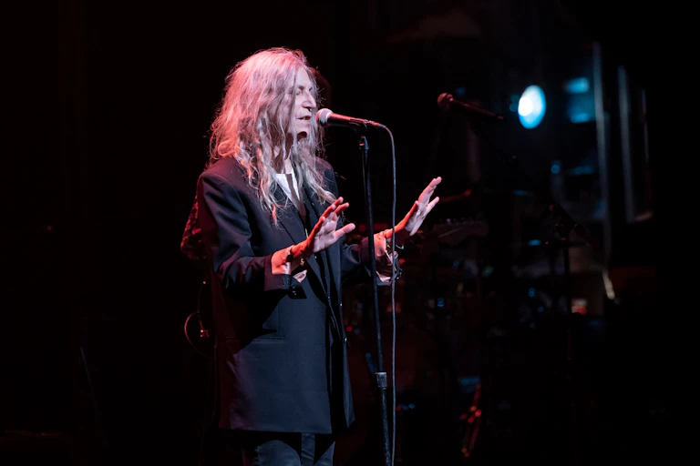 An older woman dressed in black on stage singing