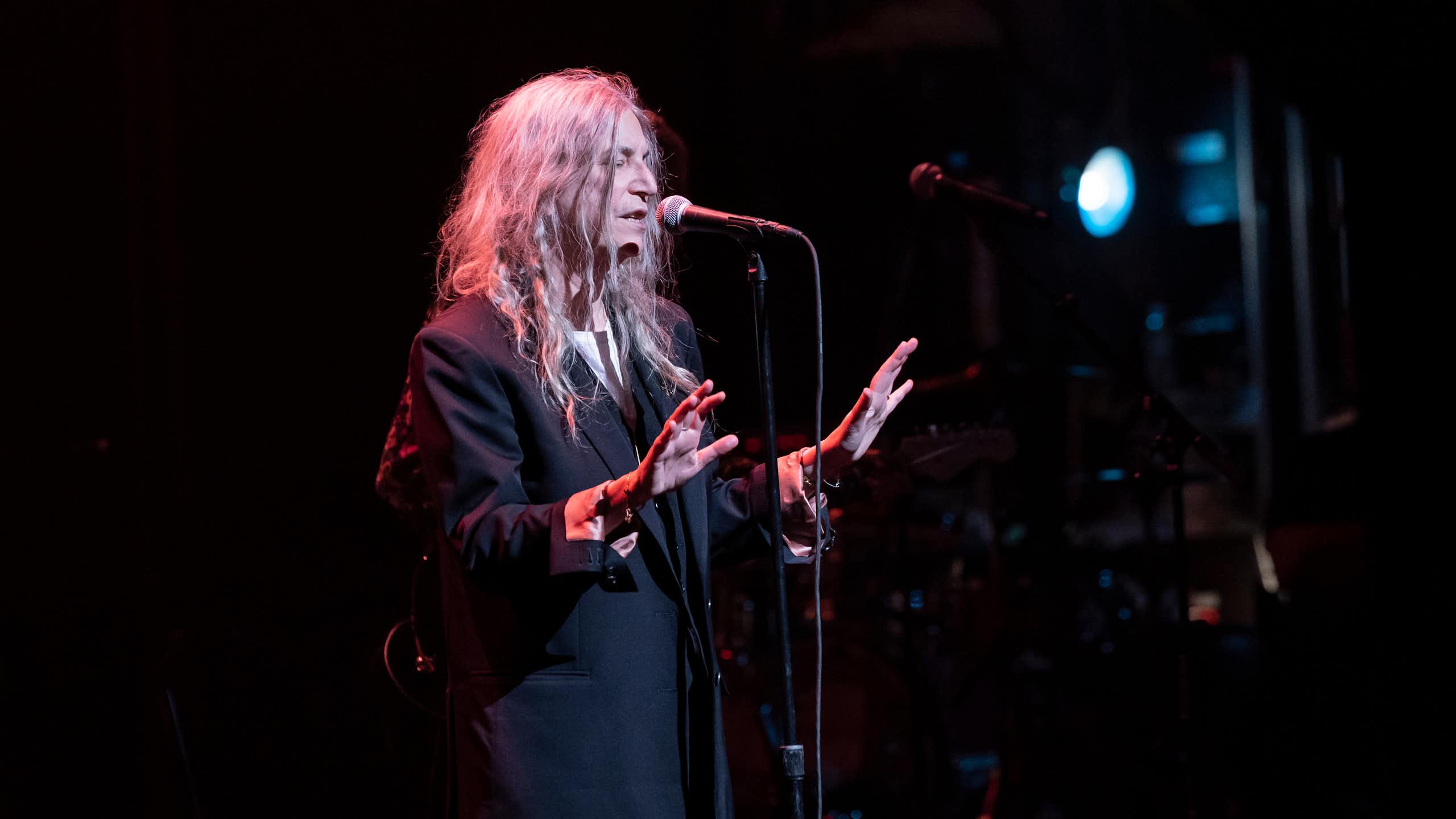 An older woman dressed in black on stage singing