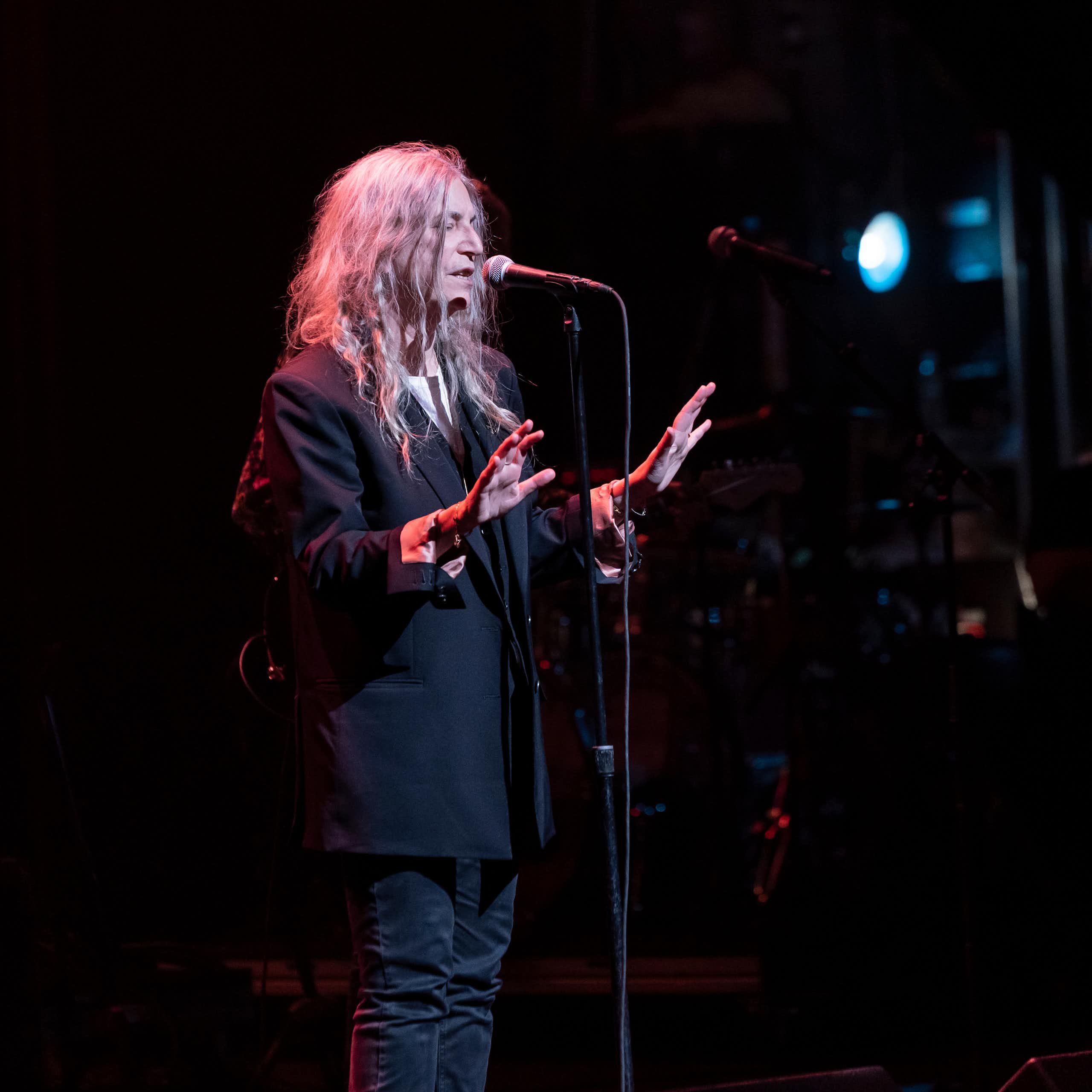 An older woman dressed in black on stage singing
