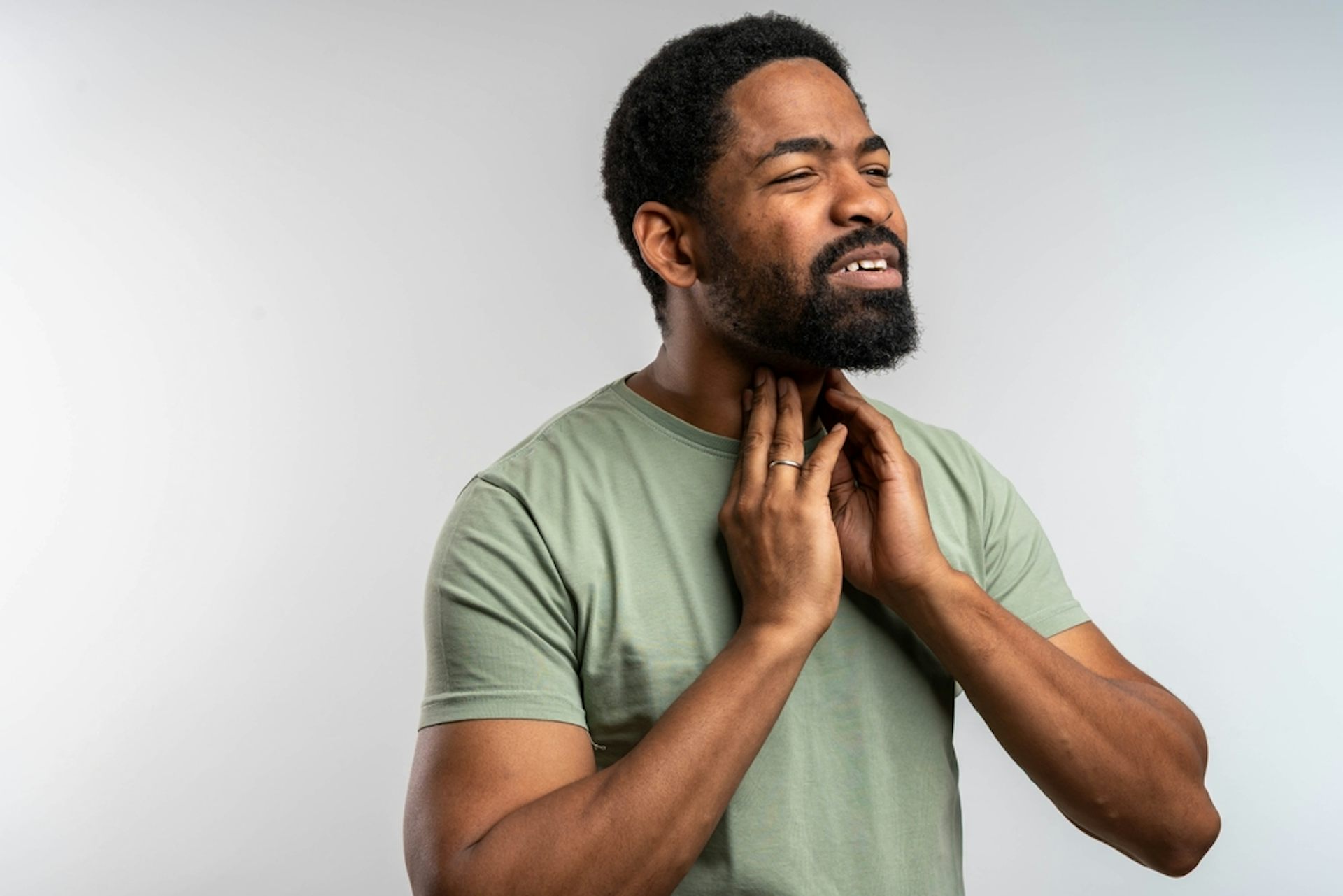 A man touching his neck, a pained look on his face.