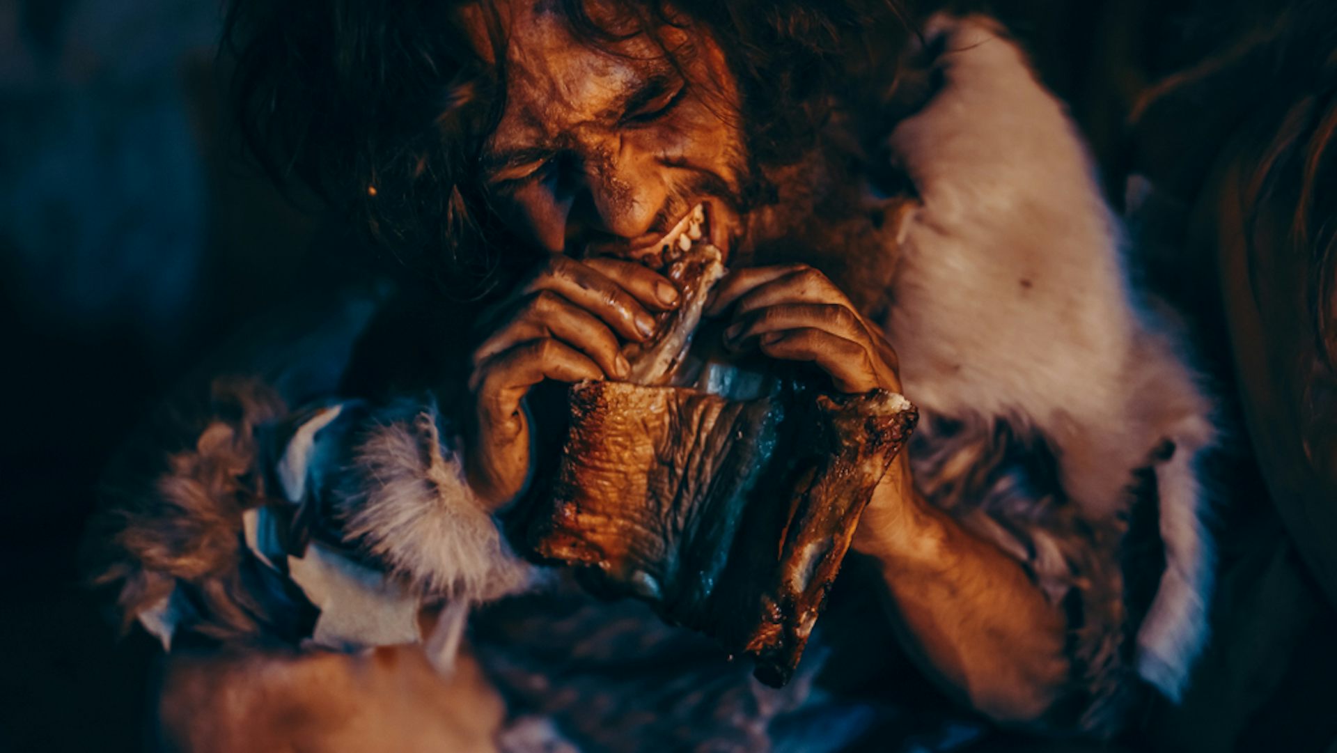 A caveman chewing on a bone.
