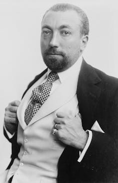 Retrato en blanco y negro de un hombre con chaleco blanco, corbata y chaqueta negra.