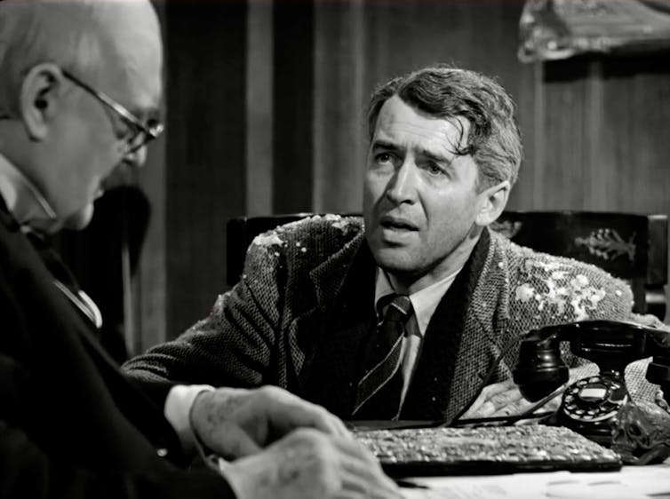 Black-and-white movie still of a distraught man with snow on his jacket.