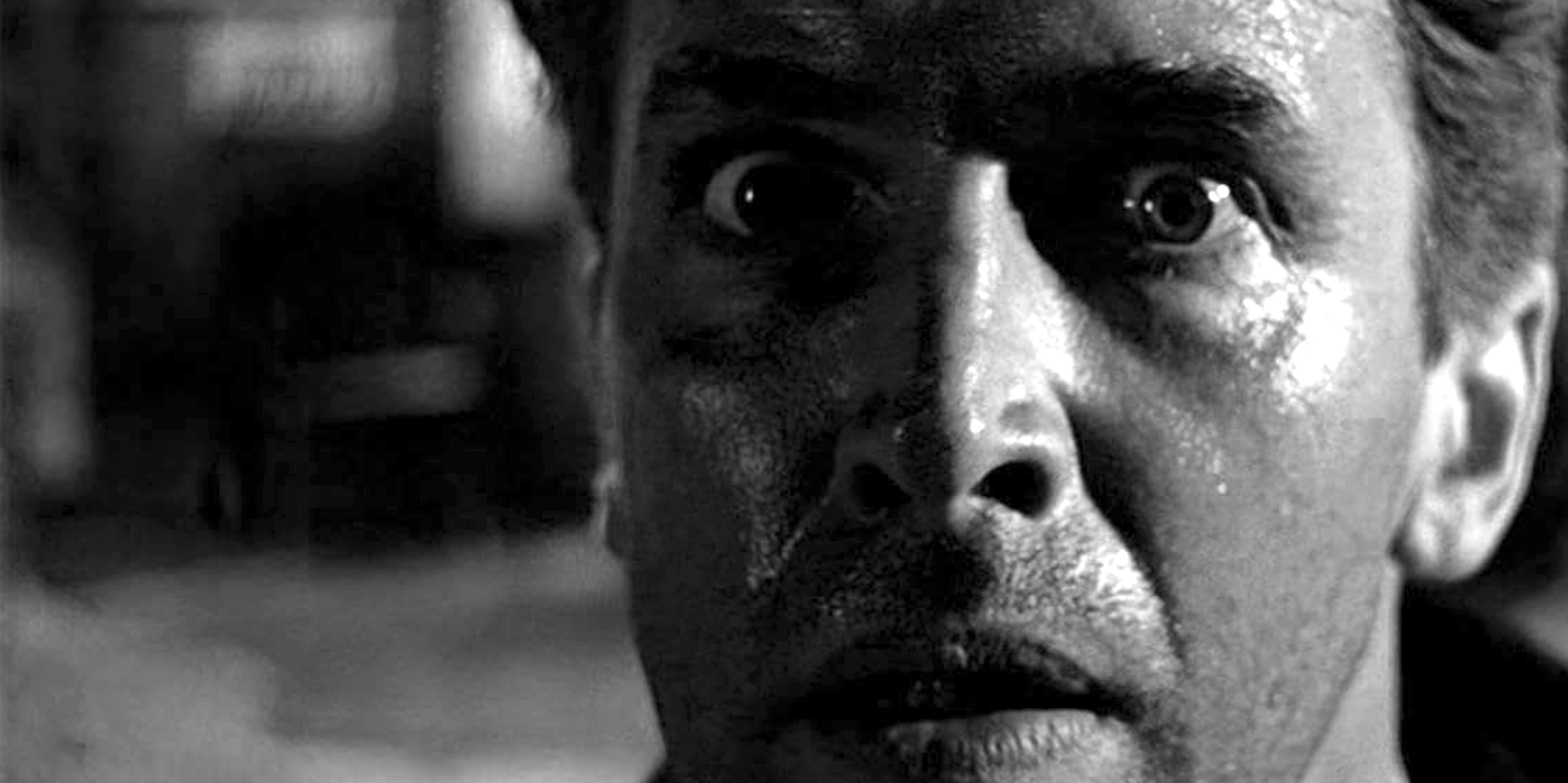 Black-and-white close-up of the face of a distraught young man.