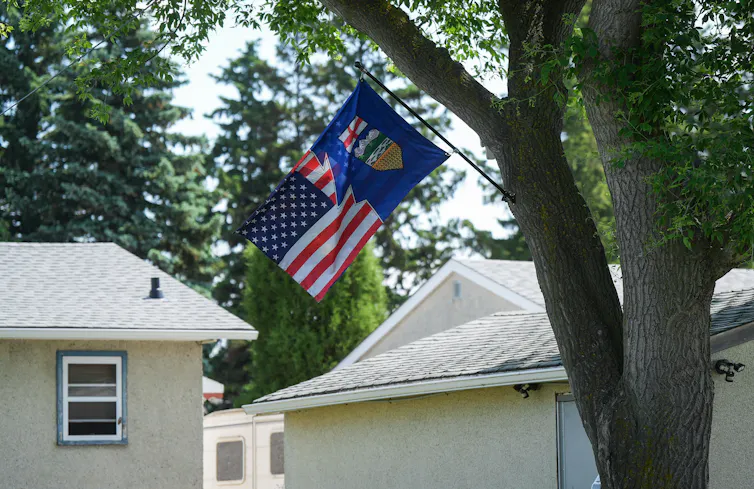 Una combinación de las banderas de Alberta y Estados Unidos cuelga en el patio delantero de alguien.