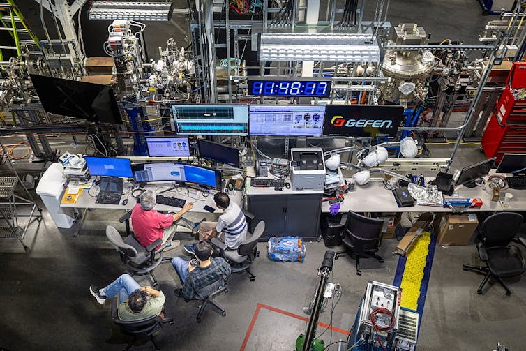 Una vista aérea de un grupo de científicos rodeados por una serie de equipos electrónicos.