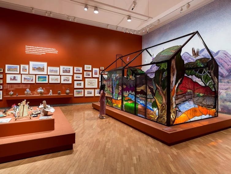 Works in a gallery, including a large stained-glass house.