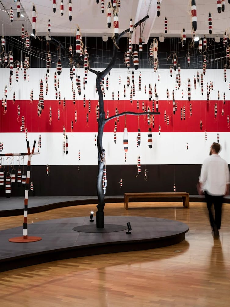 A man walks under a fantastical tree.