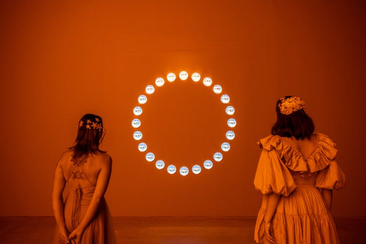 Two women look at a circle of glass spheres.