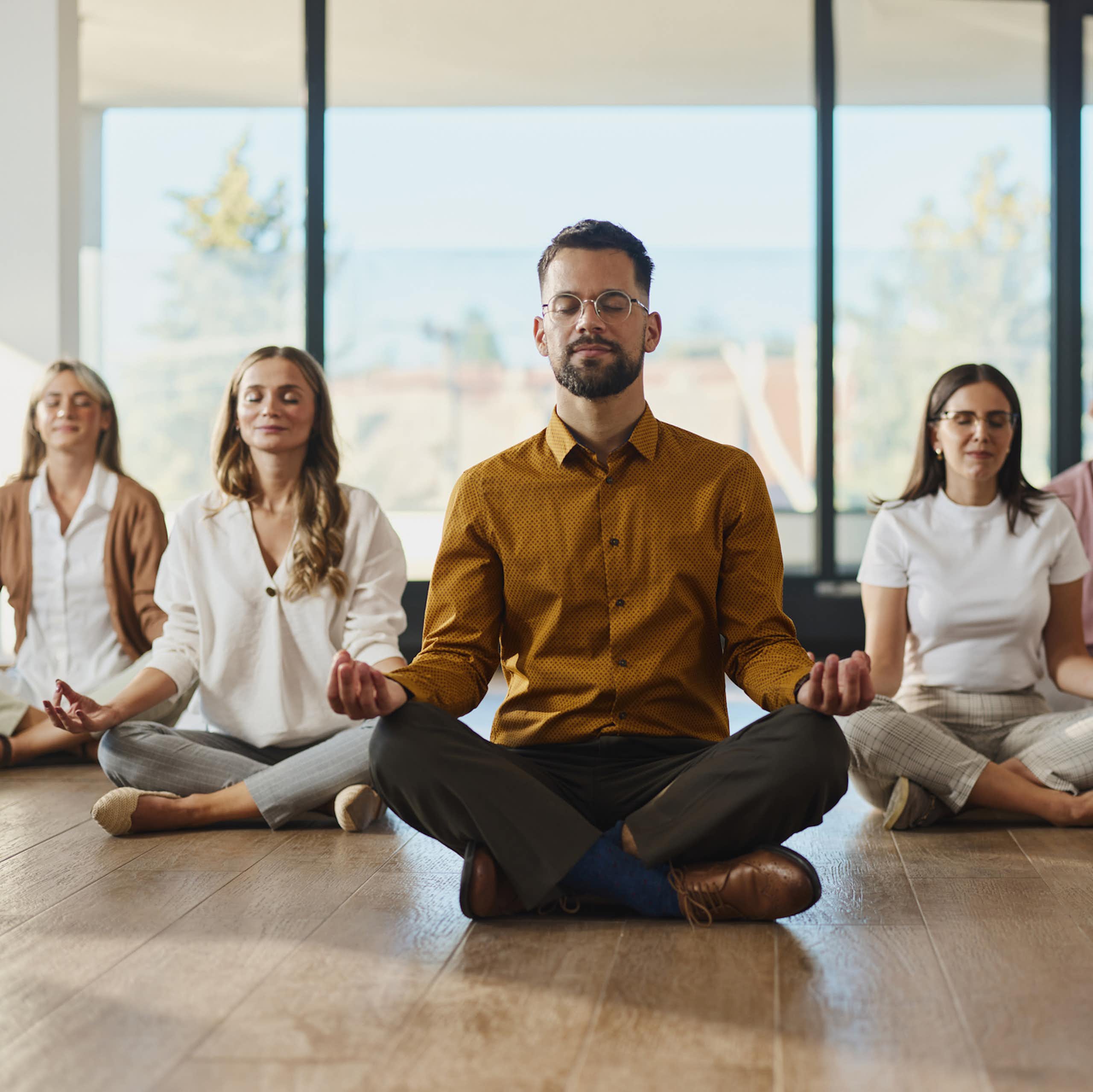 Lima orang bermeditasi dengan mata terpejam sambil duduk dalam posisi teratai