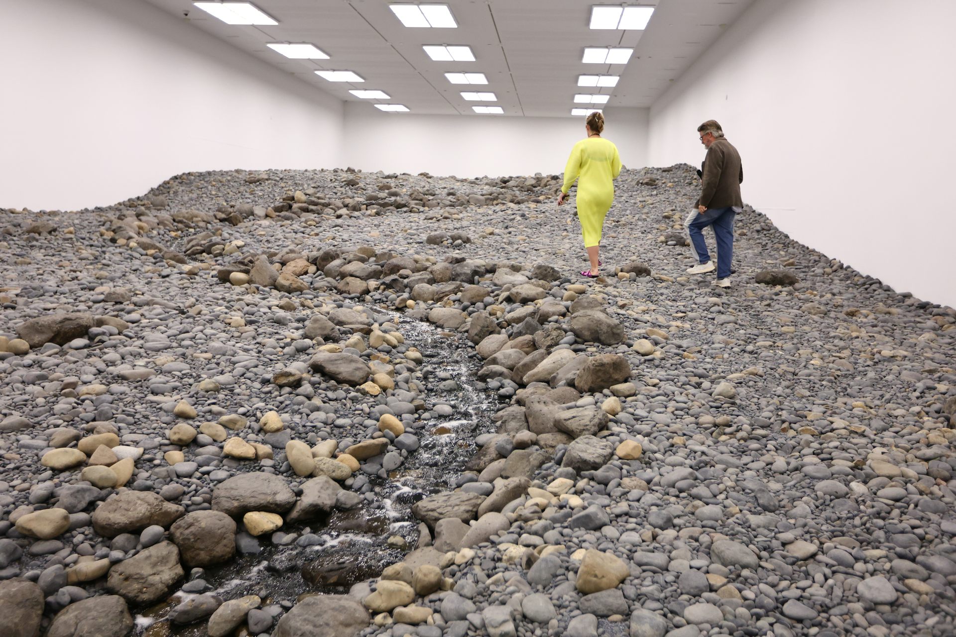 Two people climb over a rocky landscape inside. 