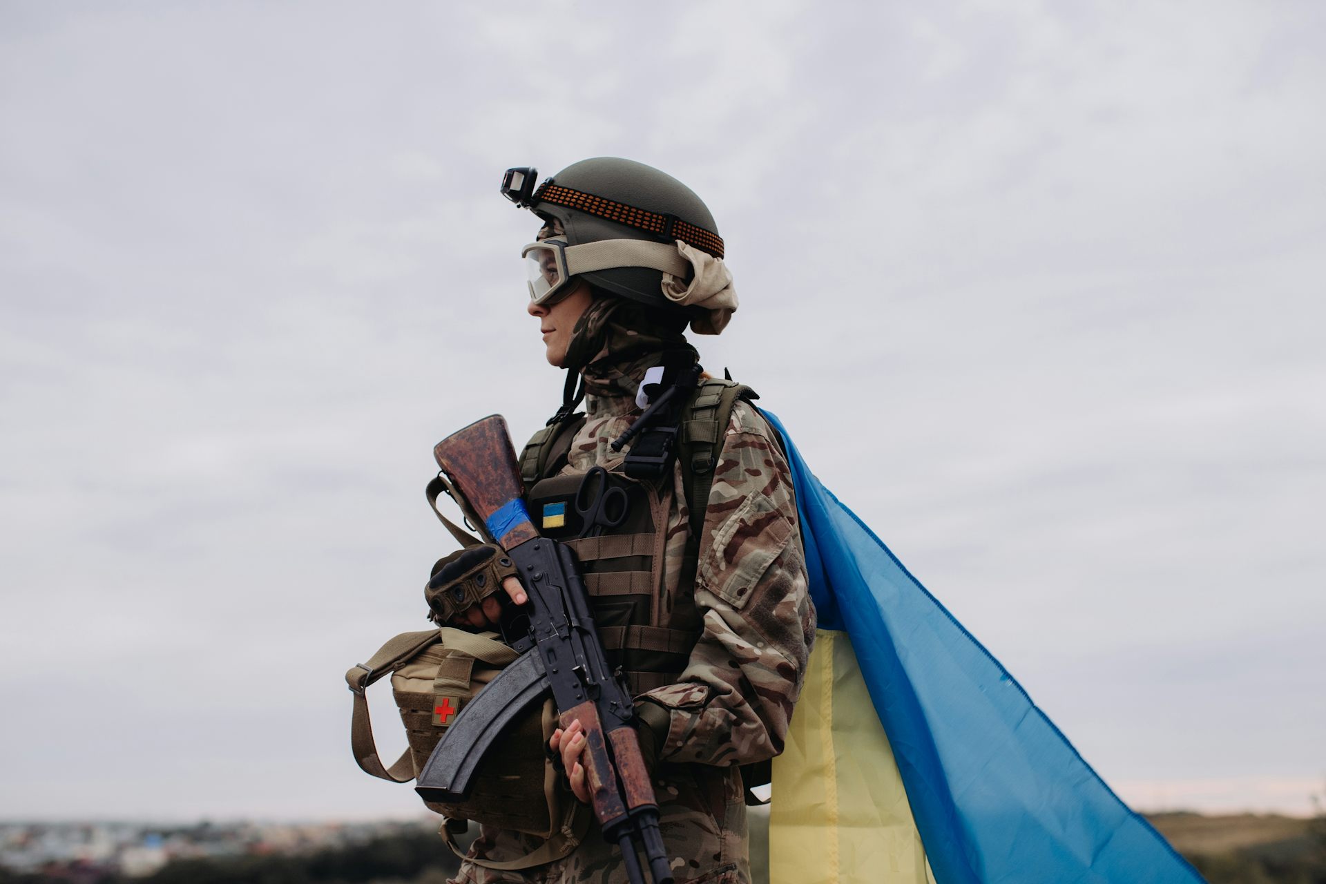 A female soldier in the Ukrainian army with a Ukraine flag wrapped around her.