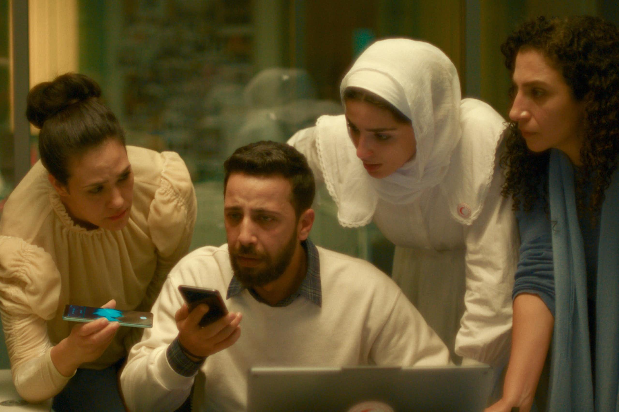 Cuatro personas hablan por un teléfono móvil puesto en altavoz.