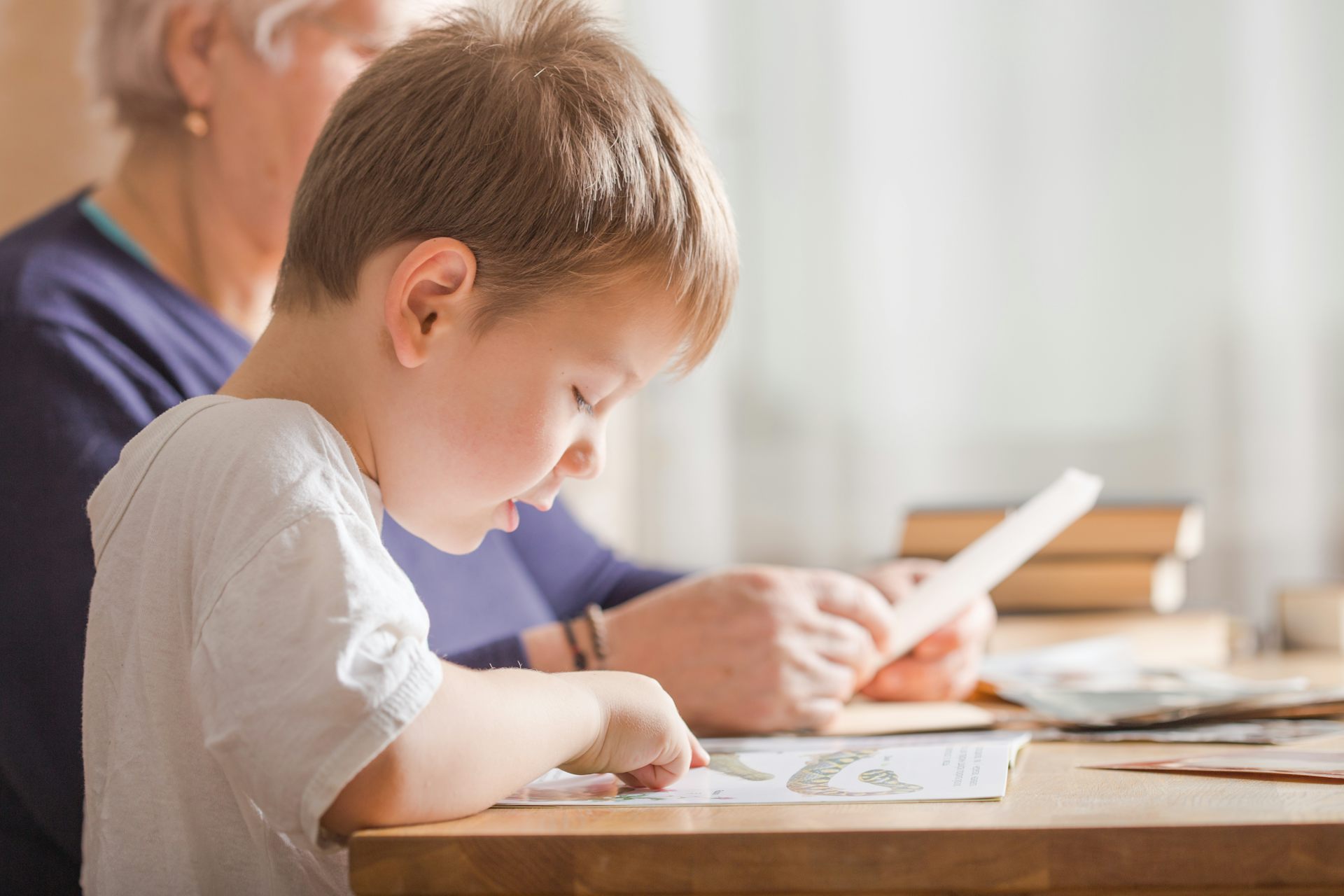 Little boy reading next to adult