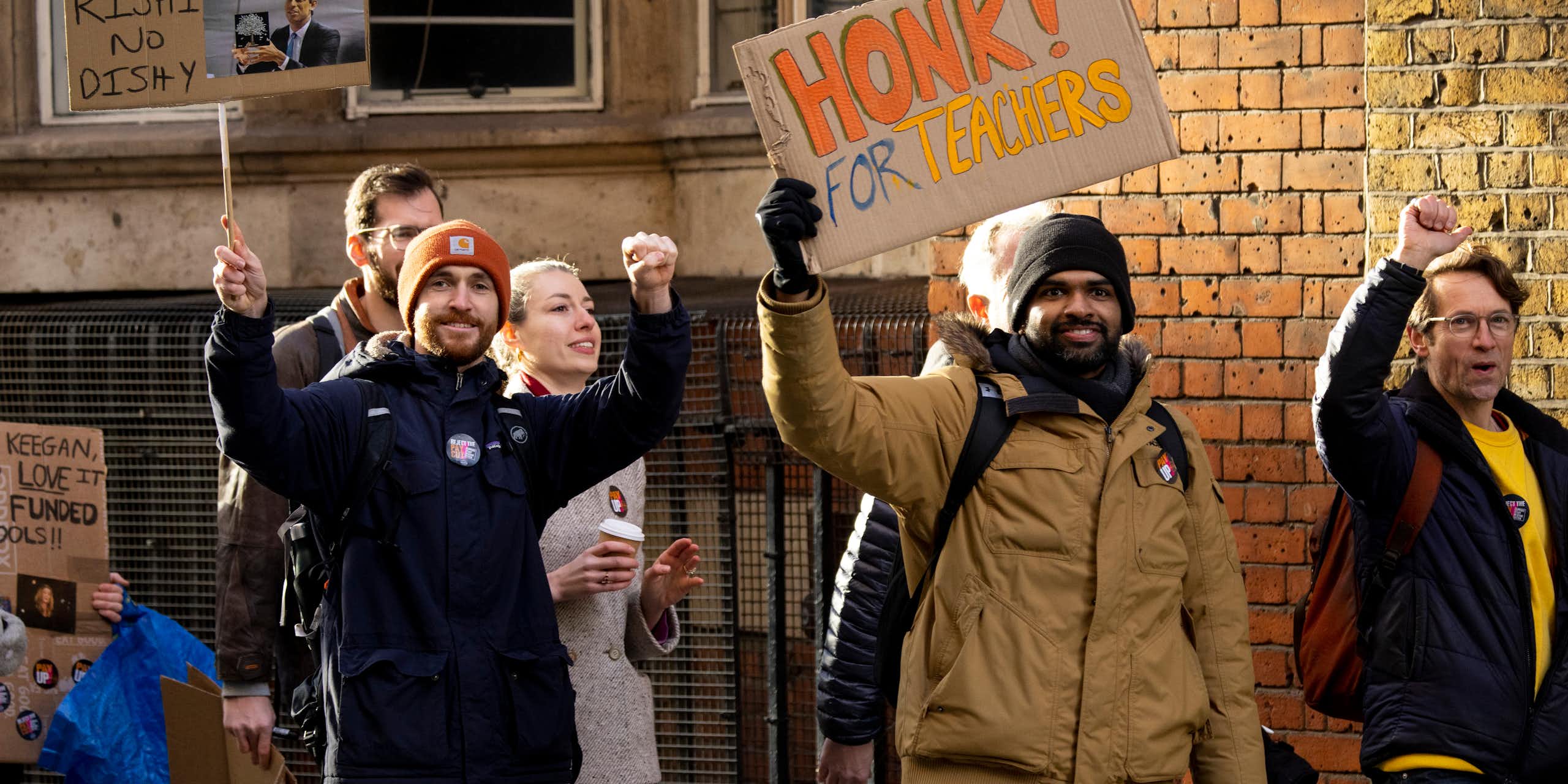 striking teachers on a picket line with one holding up a sign saying honk for teachers
