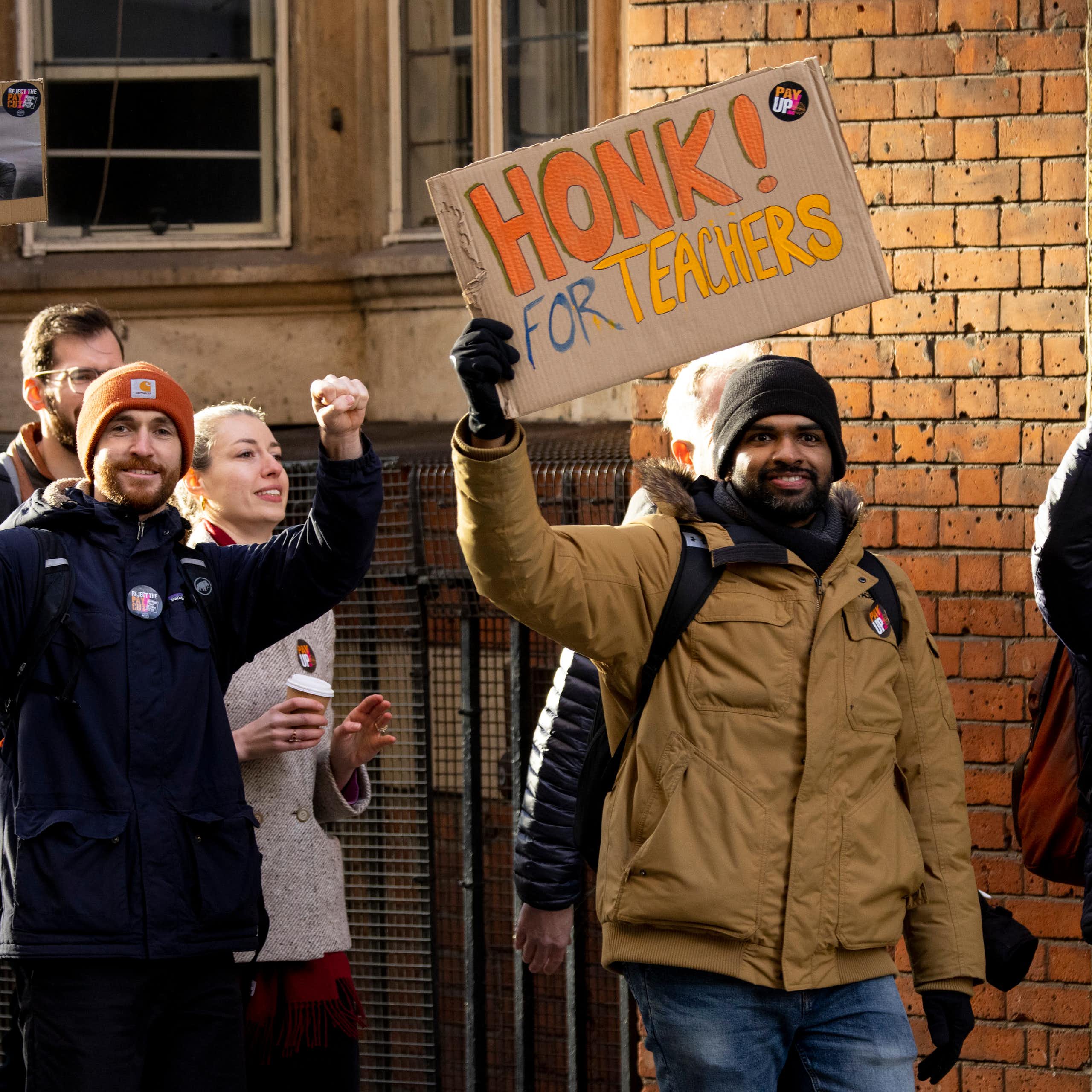 striking teachers on a picket line with one holding up a sign saying honk for teachers