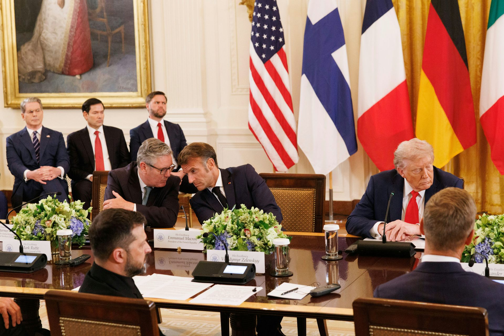 Keir Starmer and Emmanuel Macron talking while Donald Trump looks in the other direction. 